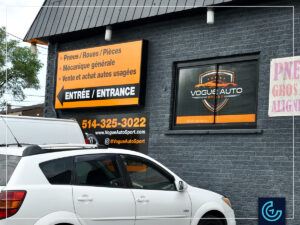 Storefront garage door and window wraps and publicity sign panels printed and installed for the auto repair shop Vogue Auto Sport.