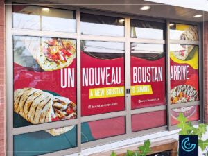 Temporary window graphics "Opening soon" as construction palisade for the new location of the restaurant franchise Boustan in Lachine.