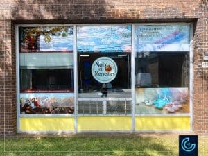Impression et installation des graphiques de vitrine publicitaires pour le magasin de noix et de paniers cadeaux Noix et Merveilles.