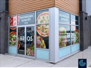 Habillage temporaire de vitrines de type palissade “Ouverture prochaine”, conçu, imprimé et installé pour le nouveau magasin de la franchise de restaurant pizza Pizzeria Bros à Beloeil.