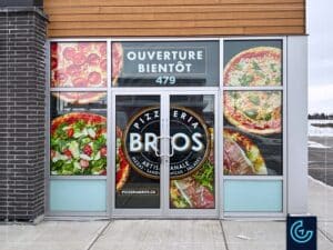 Habillage temporaire de vitrines de type palissade “Ouverture prochaine”, conçu, imprimé et installé pour le nouveau magasin de la franchise de restaurant pizza Pizzeria Bros à Beloeil.
